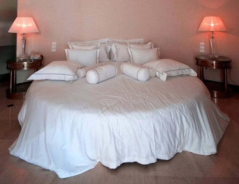Okrągłe łóżko z kolekcją poduszek